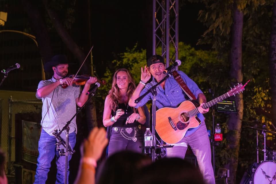 Live band with fiddle and guitars playing on an outdoor stage at night