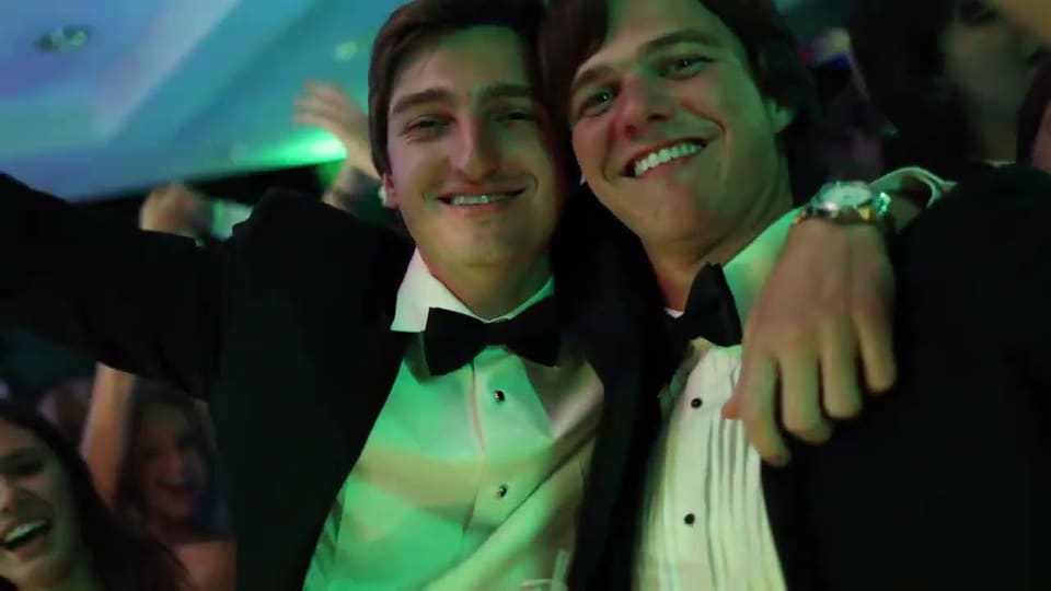 Two friends in tuxedos laughing at a formal