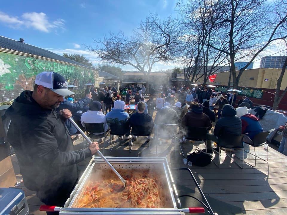 Chef stirring a crawfish boil for a crowd on an outdoor patio