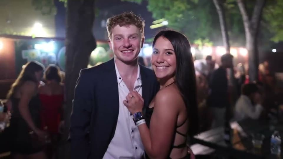 Couple in formal wear posing at an outdoor formal at night