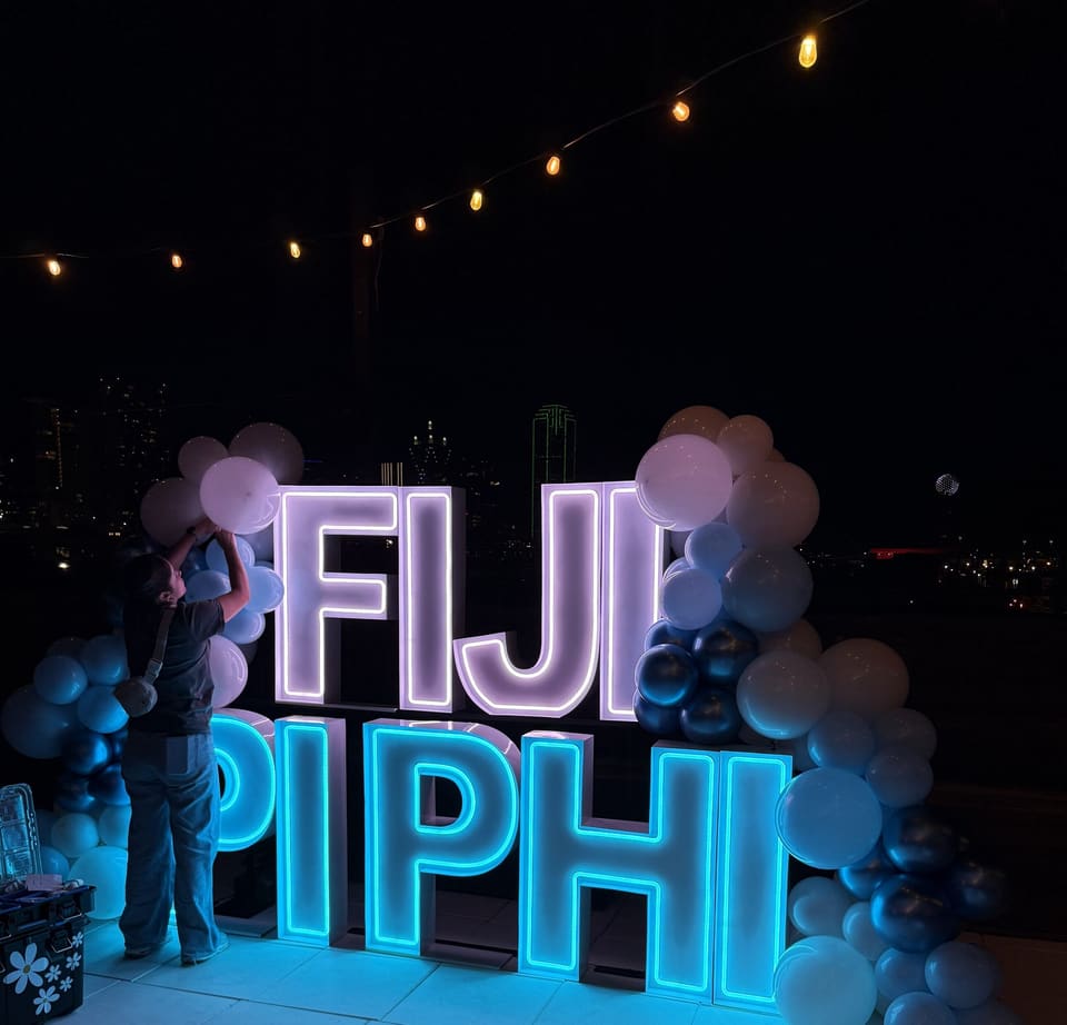Neon letter signs with blue and white balloons set up for a mixer