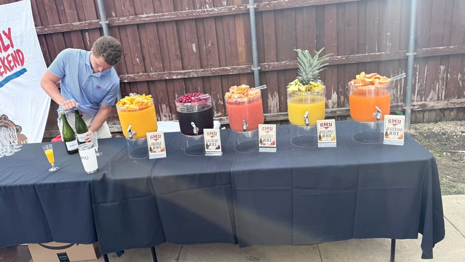 Mimosa bar with juice dispensers and fresh fruit at a parents weekend