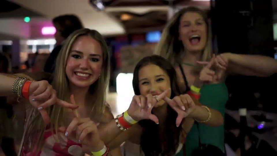 Sorority sisters making hand signs at a party