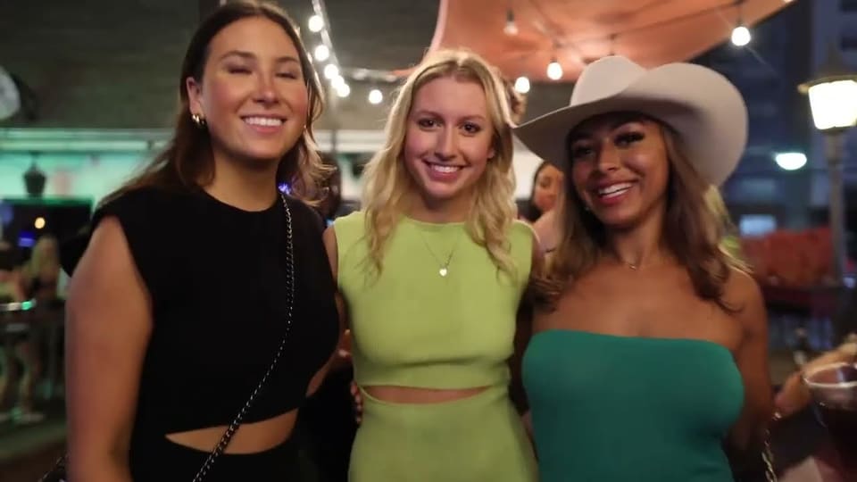 Three friends smiling on a string-lit patio