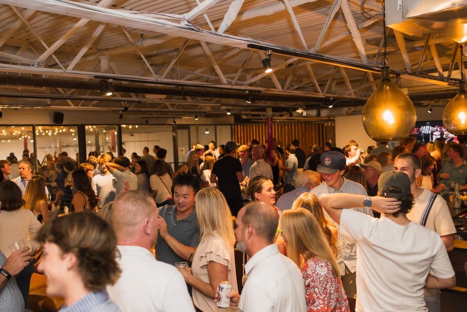 Packed venue with guests mingling under string lights
